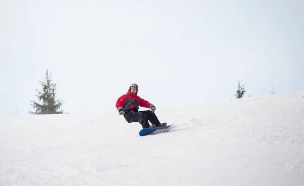 Snowboarder fährt im Winter vom Berg herunter — Stockfoto