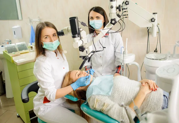 Odontóloga que trata la caries con microscopio en el consultorio del dentista —  Fotos de Stock