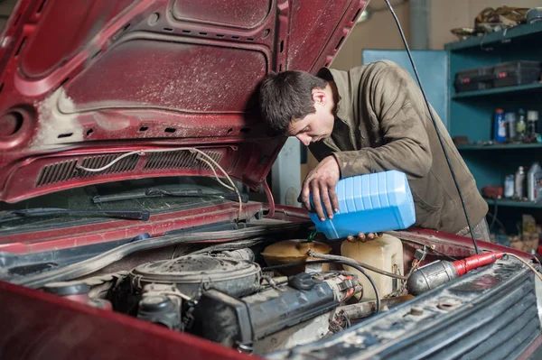 Mechanic man worker pouring antifreeze in the cooling system — Stock Photo, Image