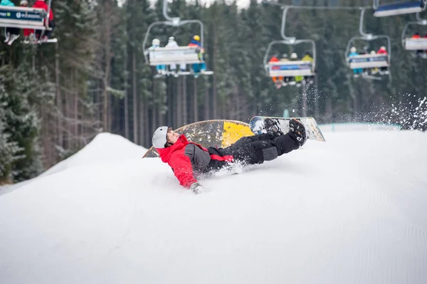 Snowboarder cai nas encostas durante o salto — Fotografia de Stock