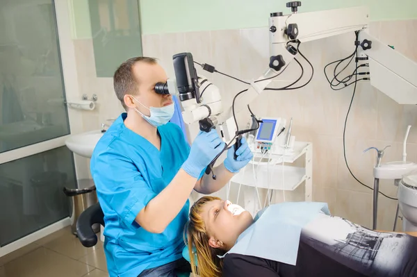Αρσενικό οδοντίατρος εργάζεται με μικροσκόπιο στο σύγχρονο οδοντιατρείο — Φωτογραφία Αρχείου