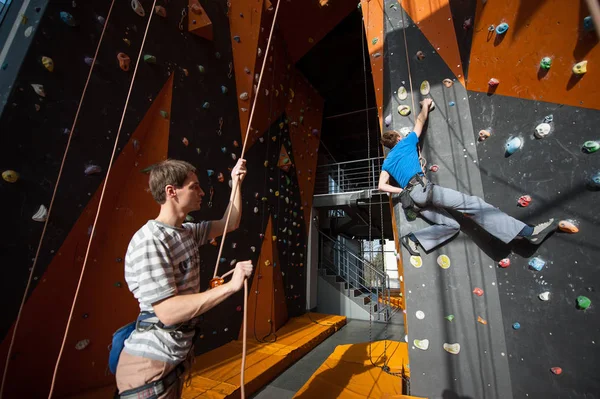 Belayer страхование альпиниста на скале стены в помещении — стоковое фото