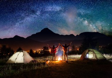 Gece kamp. Ayakta ve yukarı kaldırarak elele çift turist