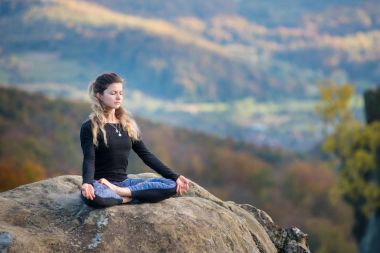 Sporty fit woman is practicing yoga on the top of the mountain clipart