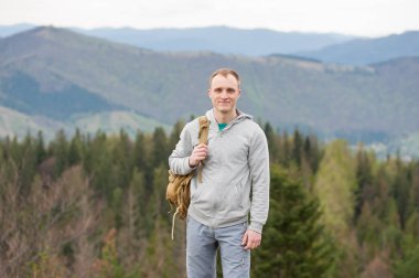 Kaya tepe üzerinde kahverengi sırt çantası ile erkek dağcı