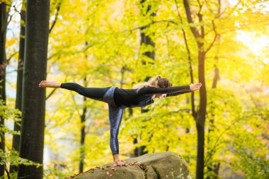 Kadın büyük taş sonbahar ormanda yoga uygulamak