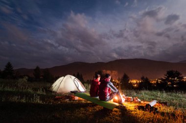 Arka plan dağlarda bulutlu gökyüzü altında oturan Çift
