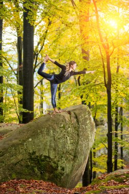 Kadın büyük taş sonbahar ormanda yoga uygulamak