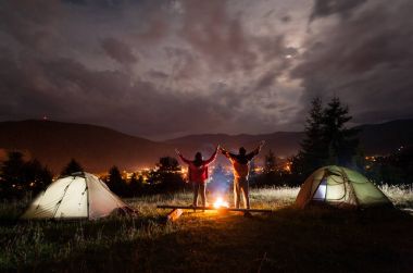 Gece kamp. Çift turist standları ve yukarı kaldırarak tutuşup
