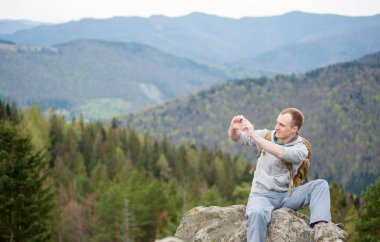 Kaya tepe üzerinde kahverengi sırt çantası ile erkek dağcı