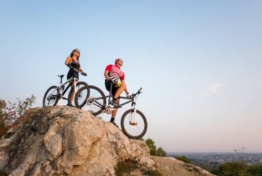 Akşam gökyüzünde mağarada bisiklet ile çift ayakta