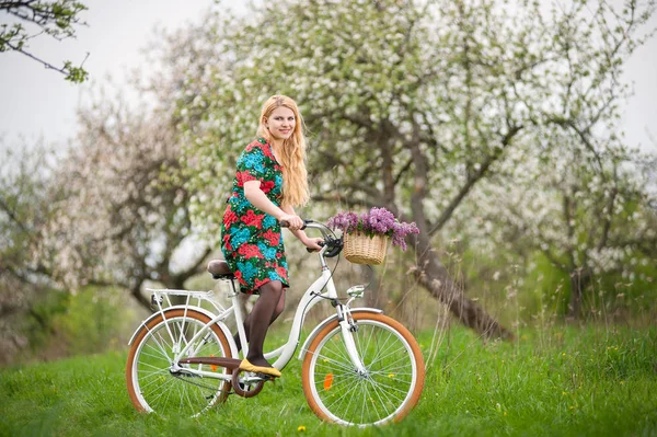 Kobiet rowerzysta z rocznika biały rower w spring garden — Zdjęcie stockowe