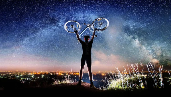 Велосипедист с велосипедом ночью под звездным небом — стоковое фото