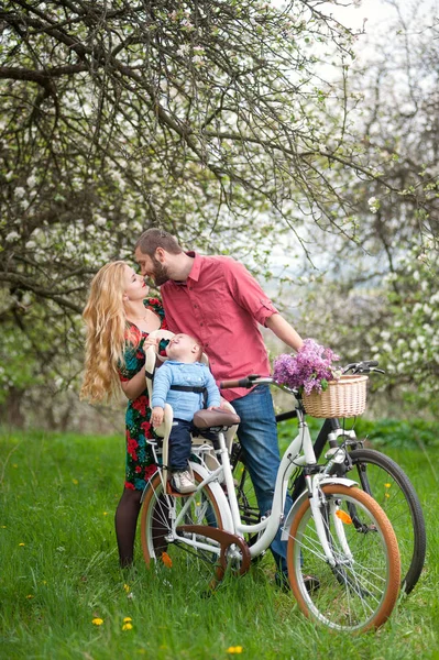 年轻的家庭，在春天的花园里的自行车 — 图库照片