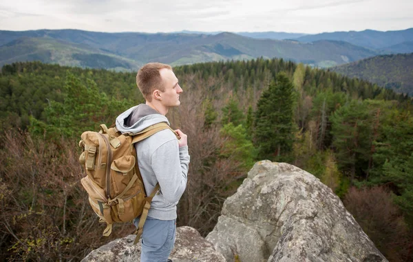 Escalador masculino con mochila marrón en la cima de la roca — Foto de Stock