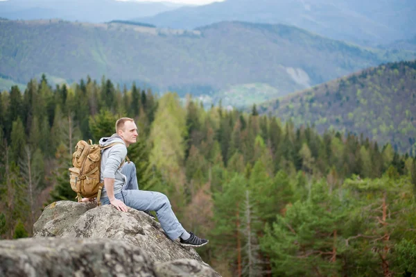 Escalador masculino con mochila marrón en la cima de la roca — Foto de Stock