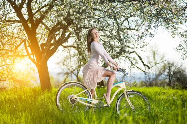 Beautiful female cyclist with retro bicycle in the spring garden — Stock Photo, Image