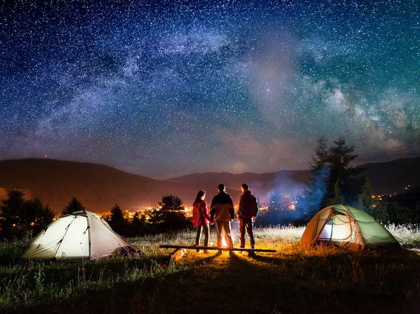 Vista trasera pareja excursionistas de pie cerca de fogata en el camping —  Fotos de Stock
