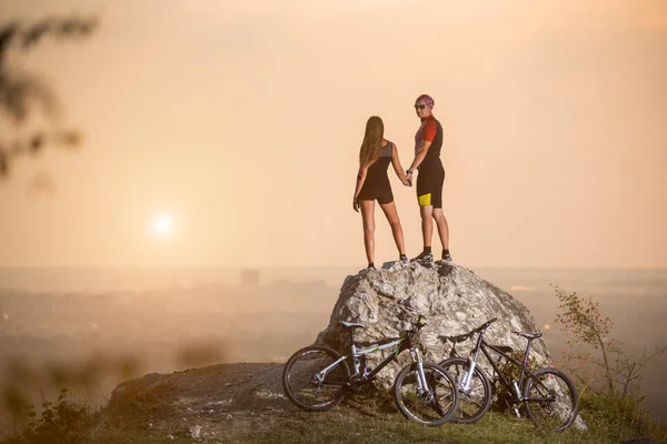 Cyclists standing on a large stone near mountain bikes — Stock Photo, Image