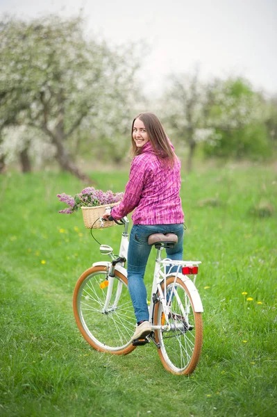 여성 사이클 봄 정원에서 빈티지 화이트 자전거를 타고 — 스톡 사진