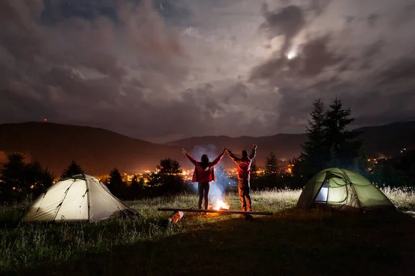 Night camping. Romantic couple standing and holding hands lifting up — Stock Photo, Image
