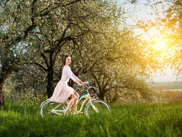 Hermosa ciclista femenina con bicicleta retro en el jardín de primavera — Foto de Stock