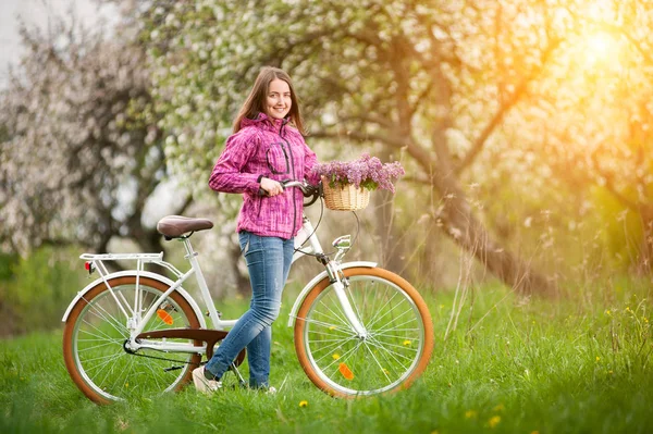 Ciclista femenina con bicicleta blanca vintage en jardín de primavera — Foto de Stock
