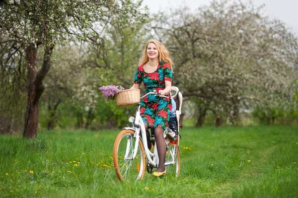 Blonde female riding city bicycle with baby in bicycle chair — Stock Photo, Image