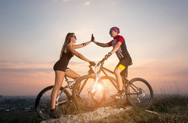 夕日の丘の上にマウンテン バイクとサイクリスト カップル — ストック写真