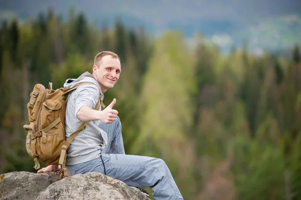 Αρσενικό ορειβάτης με καφέ σακίδιο στην κορυφή του βράχου — Φωτογραφία Αρχείου