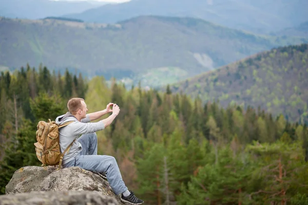 Escalador masculino con mochila marrón en la cima de la roca — Foto de Stock
