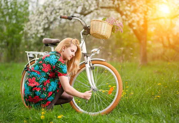 Ciclista femenina con bicicleta blanca vintage en jardín de primavera — Foto de Stock