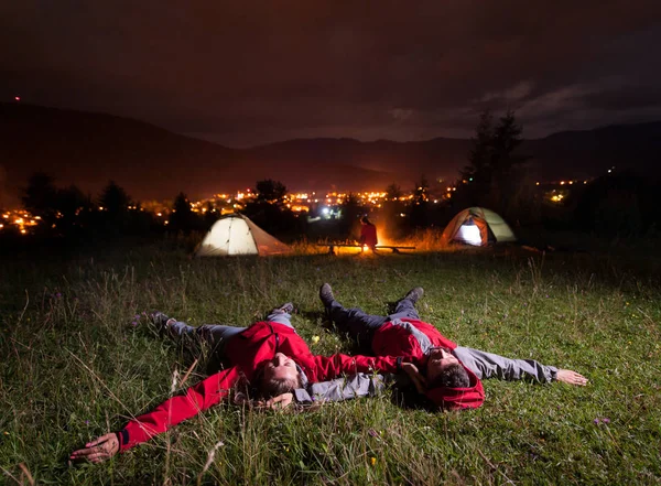 Man och kvinna du beundrar kvällshimlen, liggande på gräset — Stockfoto