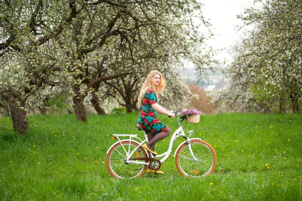 Woman riding vintage white bicycle with flowers basket — Stock Photo, Image