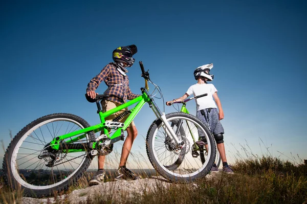 Radfahrer mit Mountainbikes auf dem Hügel unter blauem Himmel — Stockfoto