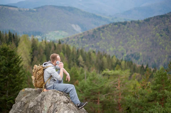 Escalador masculino con mochila marrón en la cima de la roca — Foto de Stock