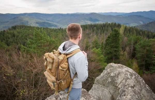 Escalador masculino con mochila marrón en la cima de la roca — Foto de Stock