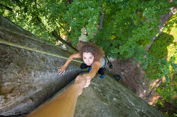 Bergsteigerin hilft Bergsteigerin, einen Gipfel zu erreichen — Stockfoto
