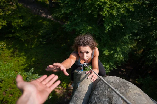 Mulher escalando em pedra grande, seu parceiro dando a mão — Fotografia de Stock