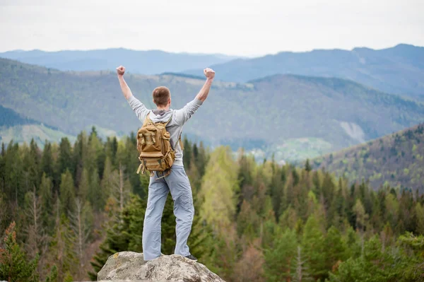 Escalador masculino con mochila marrón en la cima de la roca — Foto de Stock