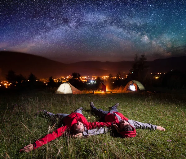 Älskande par beundrande ljusa stjärnor och liggande på gräset — Stockfoto