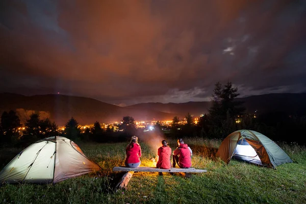 People watching fire together beside camp and tents in dark — Stock Photo, Image