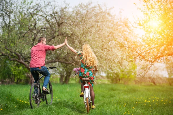 Loving young couple riding bicycles in the spring garden