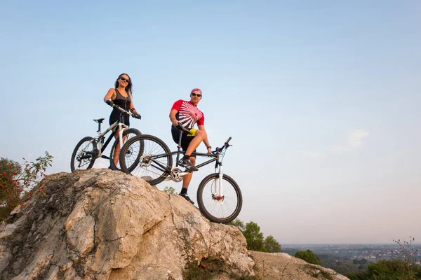 Paar steht mit Fahrrädern auf Felsen unter Abendhimmel — Stockfoto