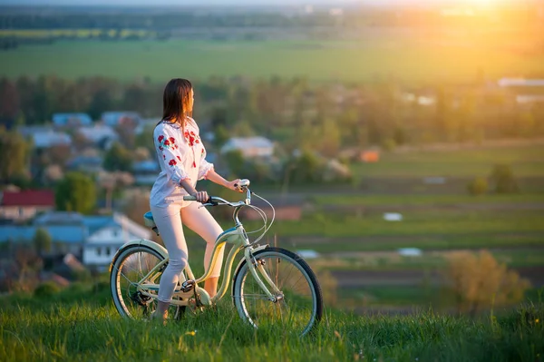 Woman with retro bike on the hill in the evening — Stock Photo, Image