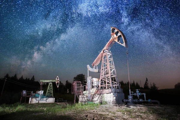 Нефтяной насос на нефтяном месторождении ночью — стоковое фото