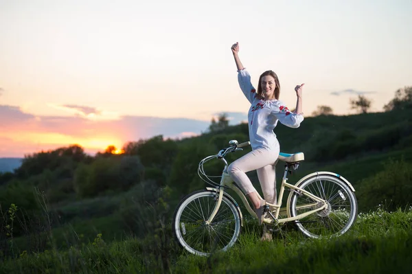 Woman with retro bike on the hill in the evening