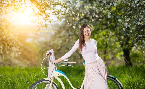 Beautiful female cyclist with retro bicycle in the spring garden — Stock Photo, Image