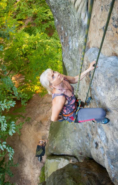 Mujer escaladora escalando en una pared rocosa — Foto de Stock