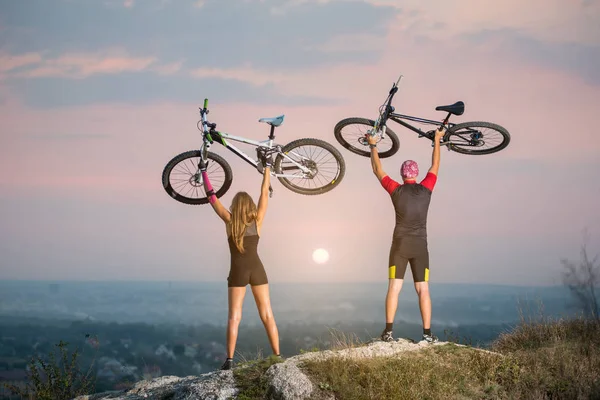 Couple bicyclist with mountain bikes on the hill at sunset — Stock Photo, Image